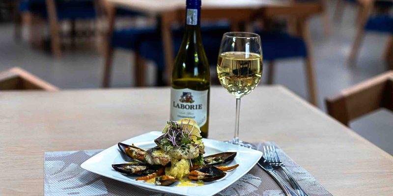 Image shows a bottle of white wine and seafood on a table at the Isijula Boutique Hotel Restaurant